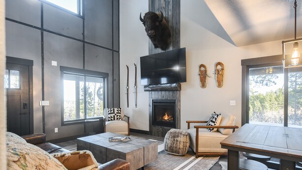 A modern living room with a fireplace, a mounted TV, and a large window. - Secluded Cabin on 3 Acres w/ Hot Tub, Open Floor Plan, Starlink Internet! (Lead)