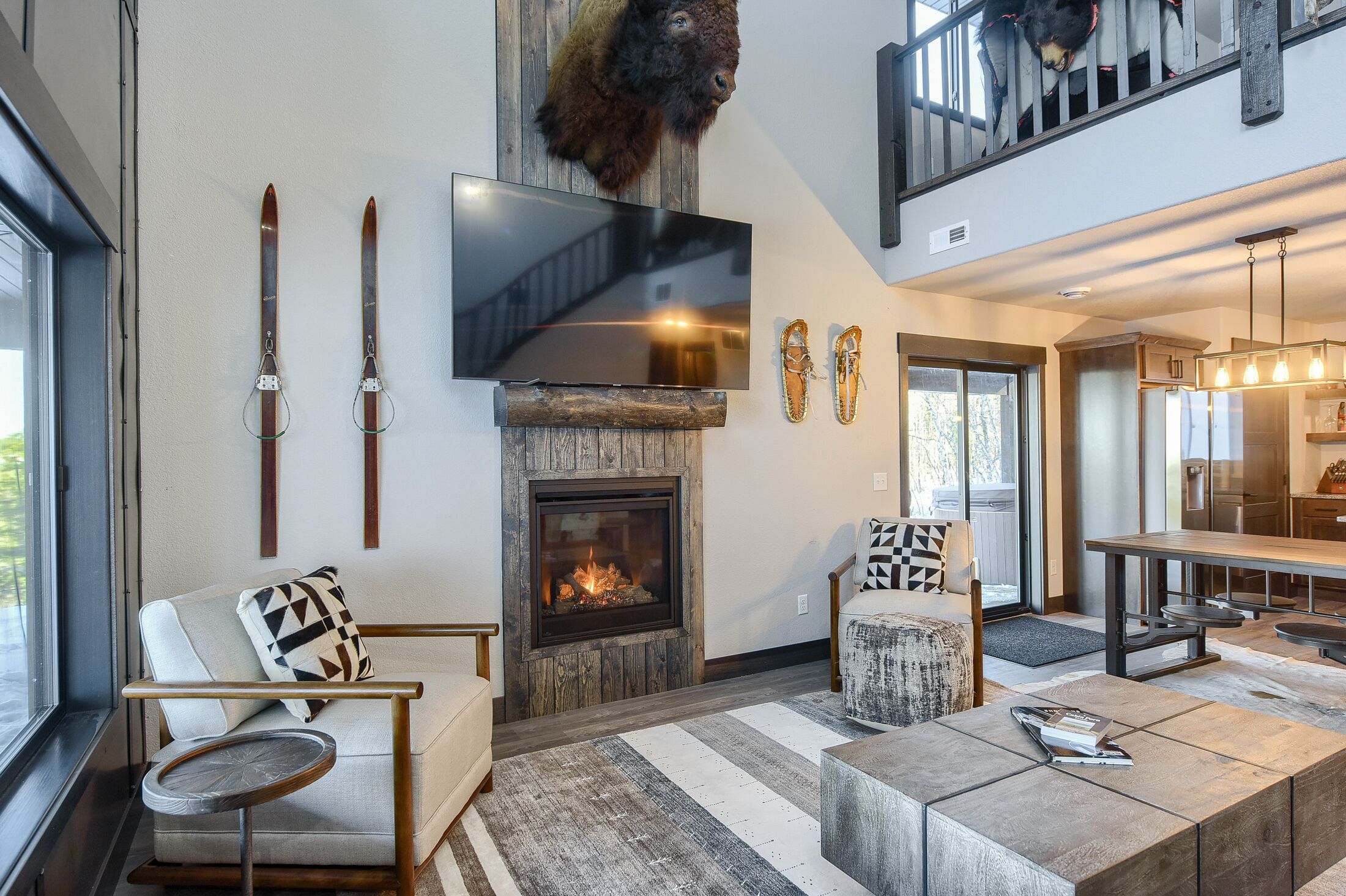 Una sala de estar moderna con chimenea, decoración temática de esquí, un televisor de pantalla plana y un comedor.