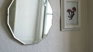 Ein Badezimmer mit einem weißen, achteckigen Spiegel und einem gerahmten Bild von Blumen an der Wand.