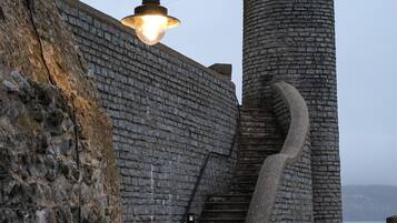 A stone staircase leading up to a turreted building, with a street lamp above.