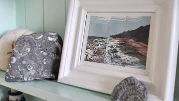 A shelf with various seashells and a framed picture of a coastal landscape.