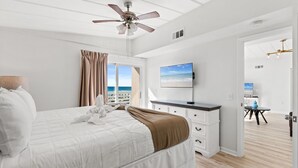 A bedroom with a bed, a ceiling fan, a TV, and a view of the beach. - CBH A - Where summer is a state of mind! (Fort Walton Beach)