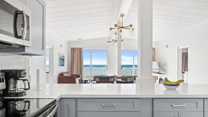 A modern kitchen with a large island, stainless steel appliances, and a view to the outside. - CBH A - Where summer is a state of mind! (Fort Walton Beach)