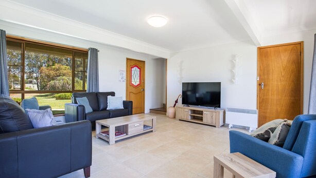 Ein modernes Wohnzimmer mit einem großen Fernseher, zwei Sofas, einem Couchtisch und einem Kamin.