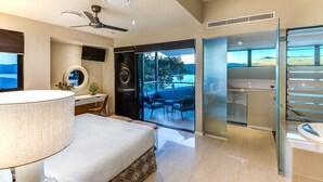 A modern hotel room with a large bed, a desk, a TV, and a balcony with a view of the sea. - Edge Apartment 7, Edge Apartment 7 by HIHA (Hamilton Island)