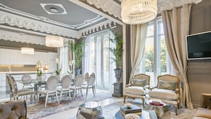A spacious living room with a large window, a dining area with a glass table, and a kitchen in the background.