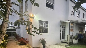 Un edificio bianco con un piccolo giardino, un vialetto in ghiaia e un prato.