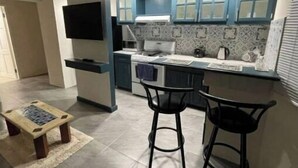 Una cucina moderna con mobili blu, forno integrato e zona pranzo con due sgabelli.