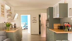 Een moderne keuken met grijze kastjes, een houten aanrechtblad en een prullenbak.