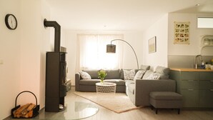 Een moderne woonkamer met een bank, een glazen salontafel, een open haard en een keukenhoek met een spoelbak en kasten.