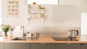Een moderne keuken met een roestvrijstalen spoelbak, een waterkoker en een plank met potten.