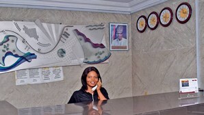 A reception desk with a marble wall, a large shoe design, and a framed picture. - Owee Suites (Lagos)
