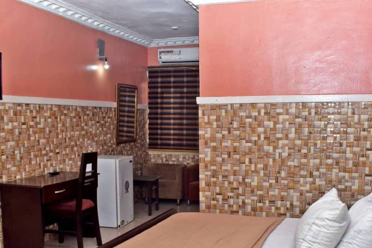 Una habitación de hotel con cama, escritorio, silla y aire acondicionado.