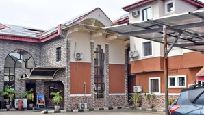 A building with a stone facade, a covered entrance, and a parked car. - Owee Suites (Lagos)