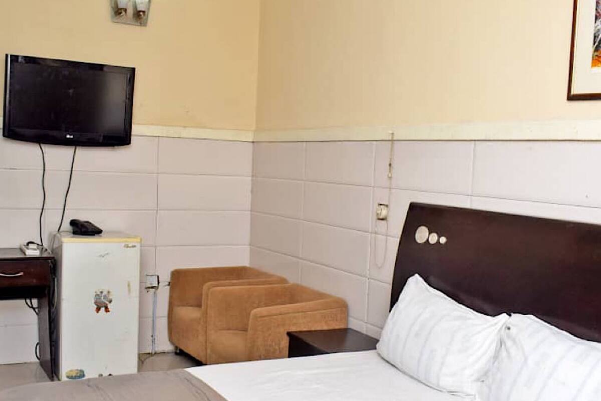 Una habitación de hotel con cama, escritorio, televisor y un refrigerador pequeño.