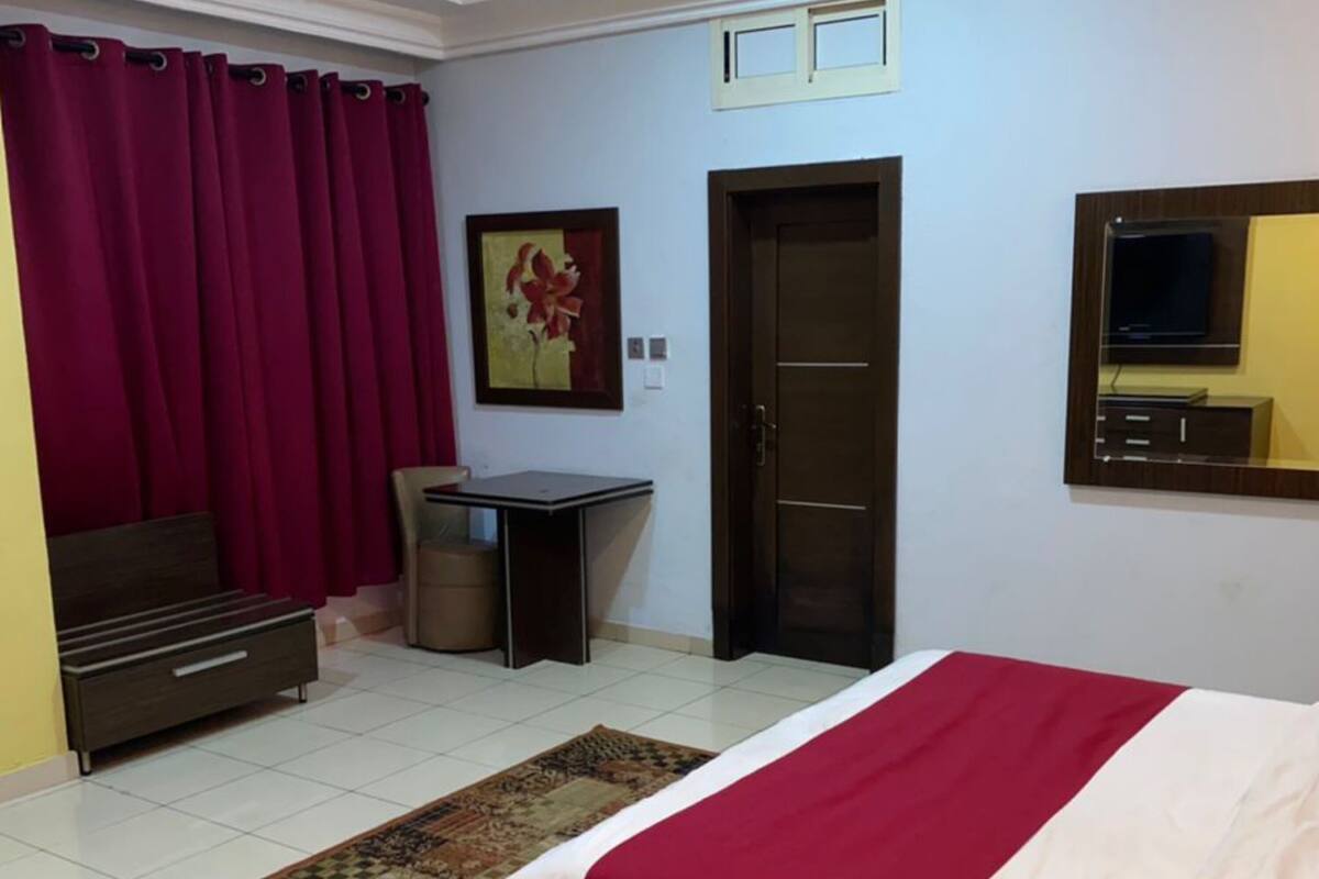 Quarto com cama, escrivaninha, cadeira, guarda-roupa, porta e janela.