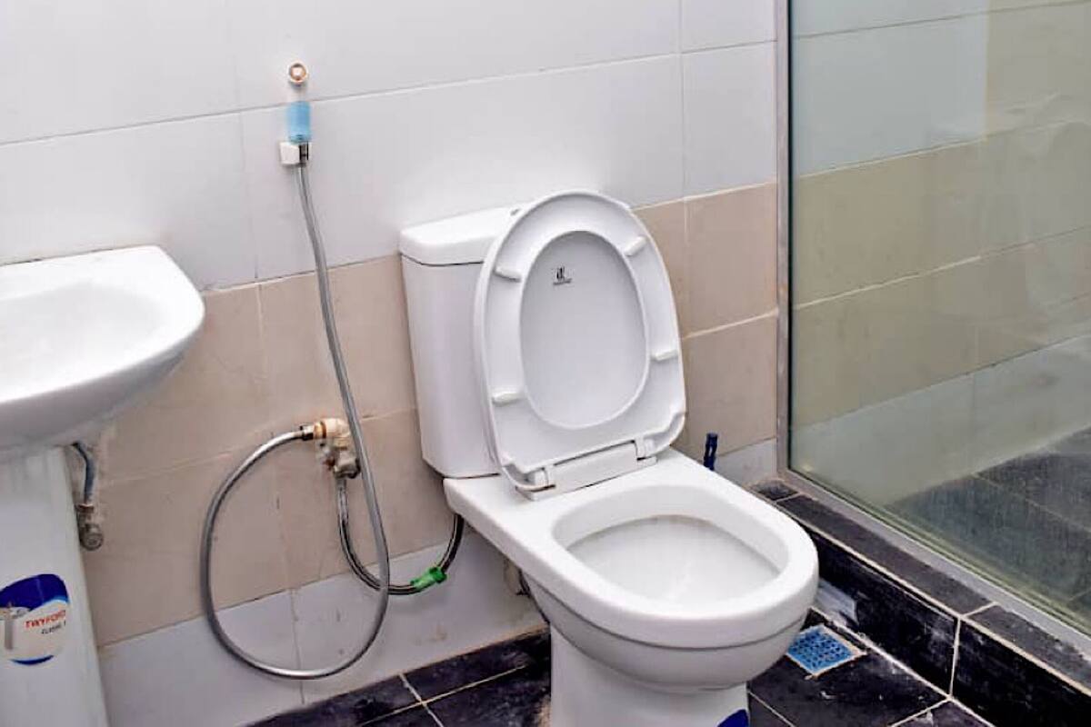Un baño con inodoro blanco, lavamanos y zona de ducha.