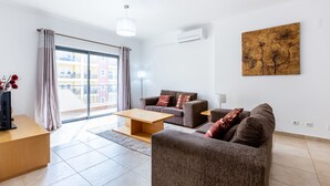Una sala moderna con un sofá, una mesa de centro y un televisor sobre un mueble de madera.