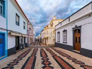 A narrow cobblestone street lined with buildings featuring traditional architecture and a patterned tile floor. - Quinta das Palmeiras - Apartment Darlene (Lagos)