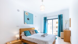 Un dormitorio moderno con una cama de madera, una alfombra azul y un cuadro en la pared.