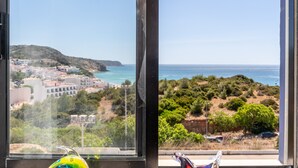 A coastal view through a window with a decorative glass vase.