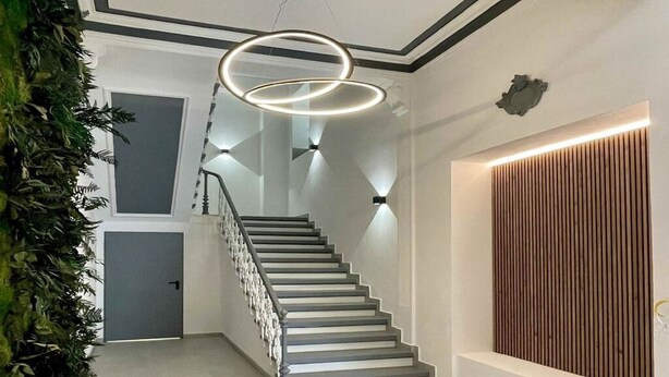 A staircase with a modern design, featuring a geometric wall pattern and a wooden panel accent. - Modern apartment Karlsruhe (Karlsruhe)