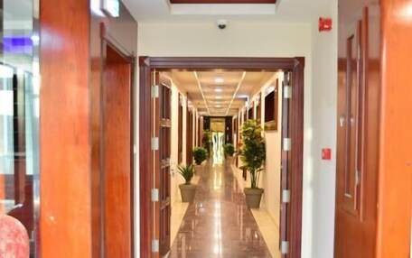 A hotel corridor with wooden doors, potted plants, and a marble floor.