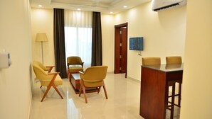Habitación de hotel con zona de comedor, televisor montado en la pared y aire acondicionado.