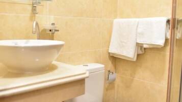 A bathroom with a white sink, toilet, and a glass shower enclosure.