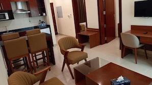 Una habitación de hotel moderna con cocina, un comedor, un sofá, una mesa de centro y un televisor.