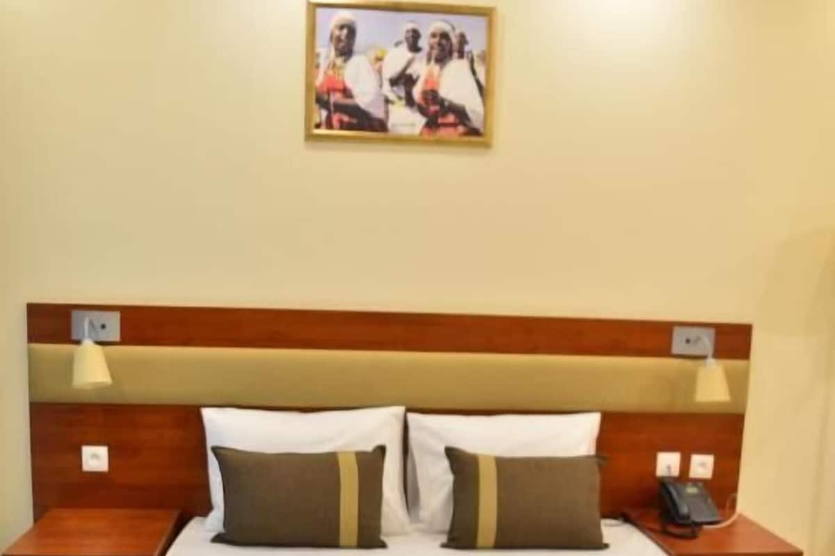 Habitación de hotel con una cama grande, dos mesitas de noche, un cabecero y un cuadro colgado en la pared.