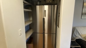 A compact kitchen with a stainless steel refrigerator, a microwave, and a small shelf with kitchenware. - Chehalis upstairs 2 bd 2 bath apartment (Chehalis)