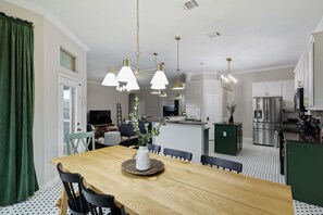 A modern kitchen with stainless steel appliances, a dining area with a wooden table and chairs, and pendant lighting. - 5-Bed/2-Bath Pool & Backyard Retreat (Waxahachie)
