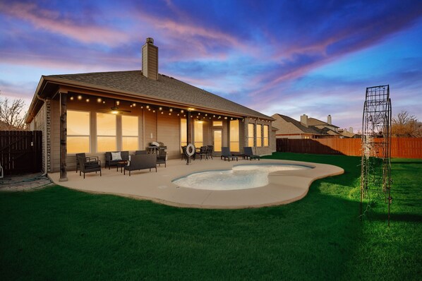 A house with a covered patio, outdoor seating, and a swimming pool.
