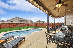 A backyard with a swimming pool, patio furniture, a barbecue grill, and a ceiling fan. - 5-Bed/2-Bath Pool & Backyard Retreat (Waxahachie)