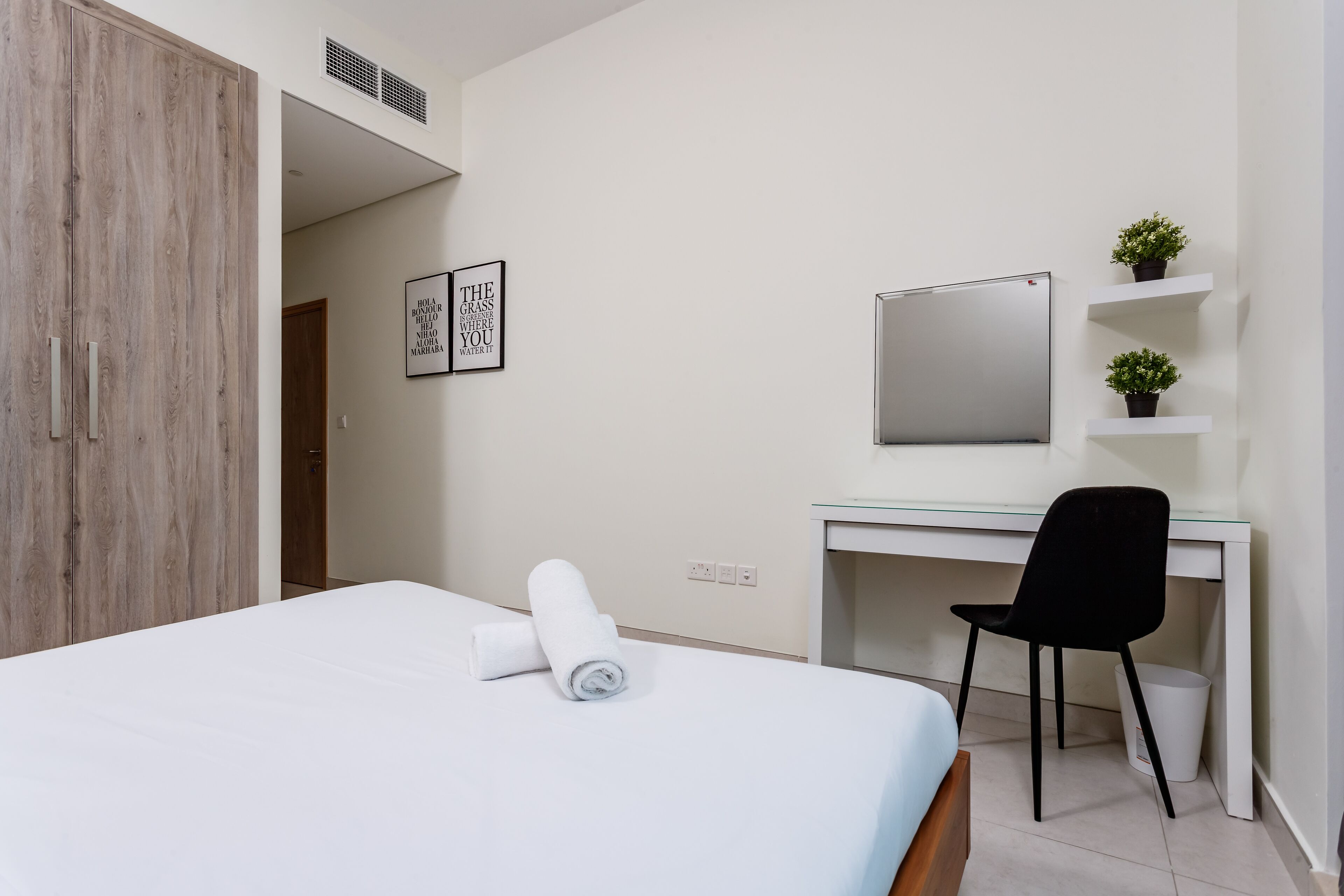 A hotel room with a bed, a desk, a chair, a TV, and a wardrobe.