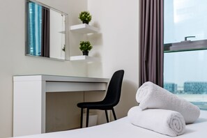 A hotel room with a bed, a desk, a chair, a mirror, and a window with a view of buildings. - Spacious 2BR apartment with rooftop pool The Bay DT by 360 Vacation (Dubai)