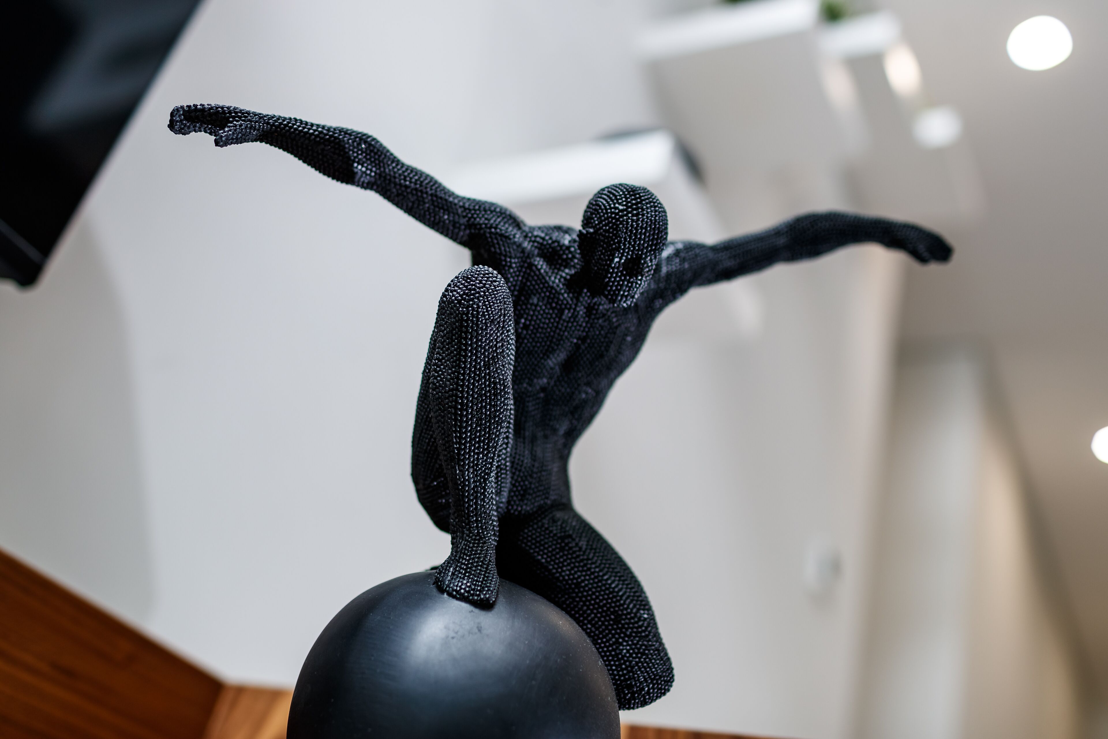 A sculpture of a figure in a dynamic pose on a spherical base.
