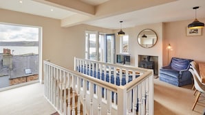A spacious living room with a view of the sea, a fireplace, and a balcony with a railing. - Host & Stay | Watch House (Scarborough)