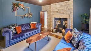 A living room with a stone fireplace, a blue sofa, and a wooden coffee table.
