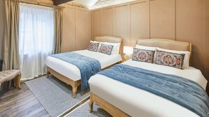A bedroom with two beds, a bench, and a patterned rug.
