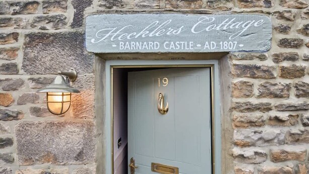A stone wall with a door labeled "Hecklers Cottage Barnard Castle AD 1807".