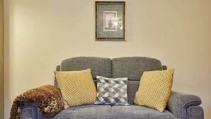 Un canapé gris agrémenté de coussins à motifs et d’un plaid à imprimé léopard.