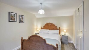 Une chambre à coucher avec un lit en bois, deux lampes de chevet et deux tableaux encadrés accrochés au mur.