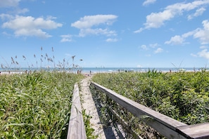 A wooden boardwalk leading to a beach with a clear sky and distant ocean view. - Direct Oceanfront Next to Cocoa Beach Pier, Heated Pool (Cocoa Beach)