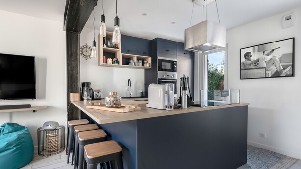 Una cucina moderna con isola centrale, sgabelli da bar e un'ampia finestra.