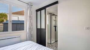 Una camera da letto con un letto, una porta scorrevole in vetro che dà su un’area doccia e una finestra con tende.