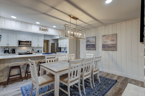 A modern kitchen with white cabinetry, a central island, and a dining area with a wooden table and chairs.