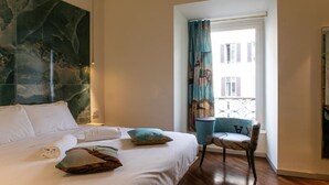 A hotel room with a large bed, a chair, a window with curtains, and a wall with a large abstract painting. - Bhr Cavour 150 (Rome)