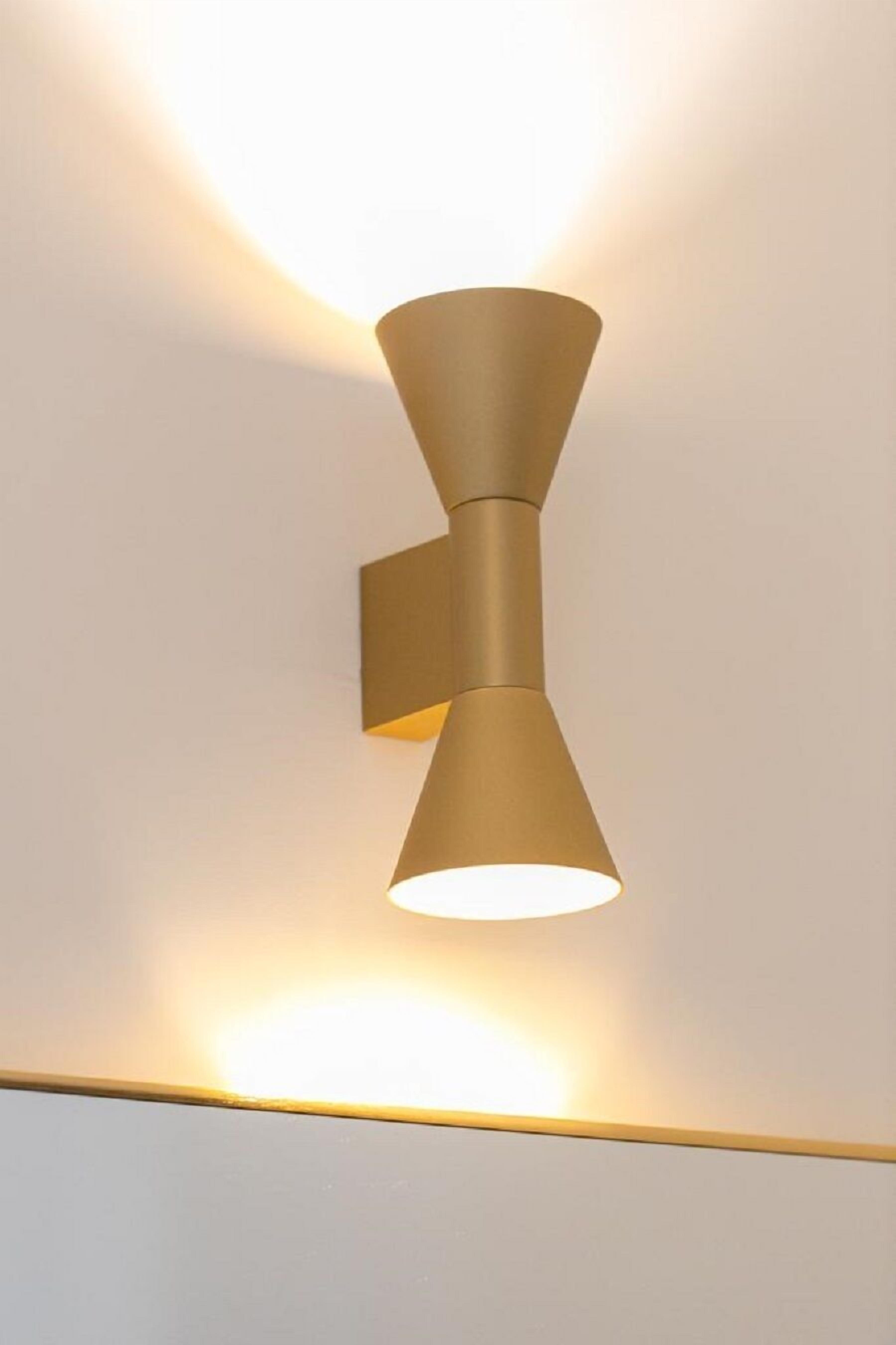 Een wandlamp met een kegelvormige lampenkap.